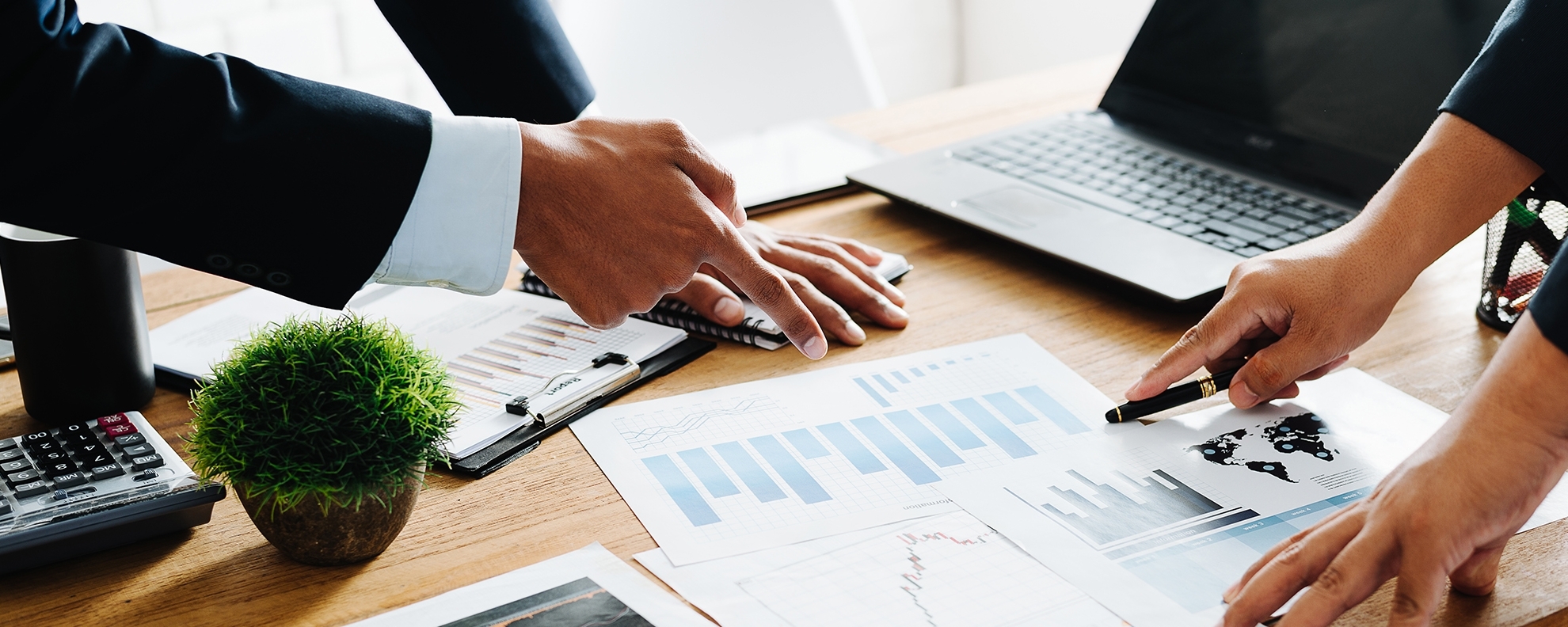 Closeup of professionals pointing at charts on desk